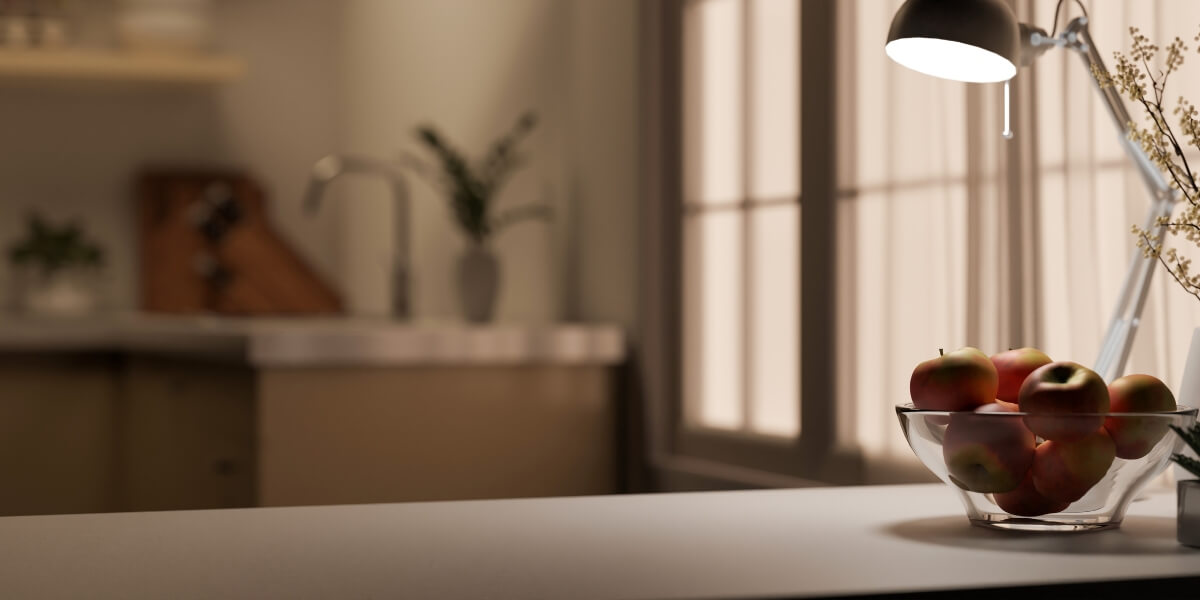 Bowl of apples on counter with desk lamp