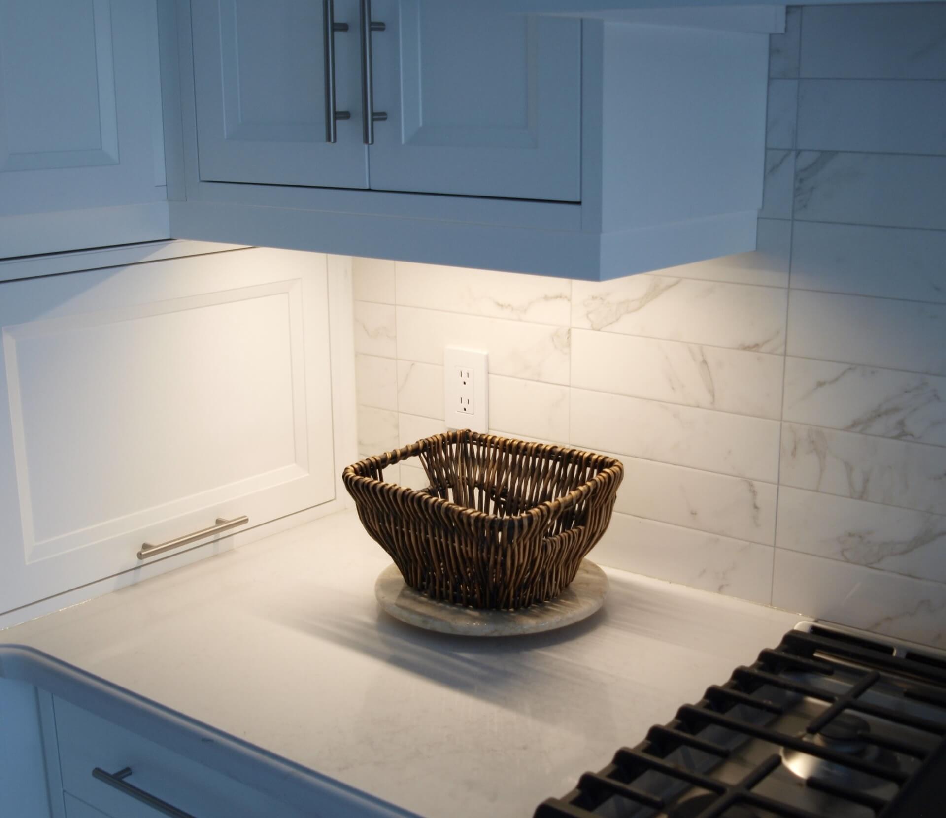 Under-cabinet lighting over a kitchen counter with fruit
