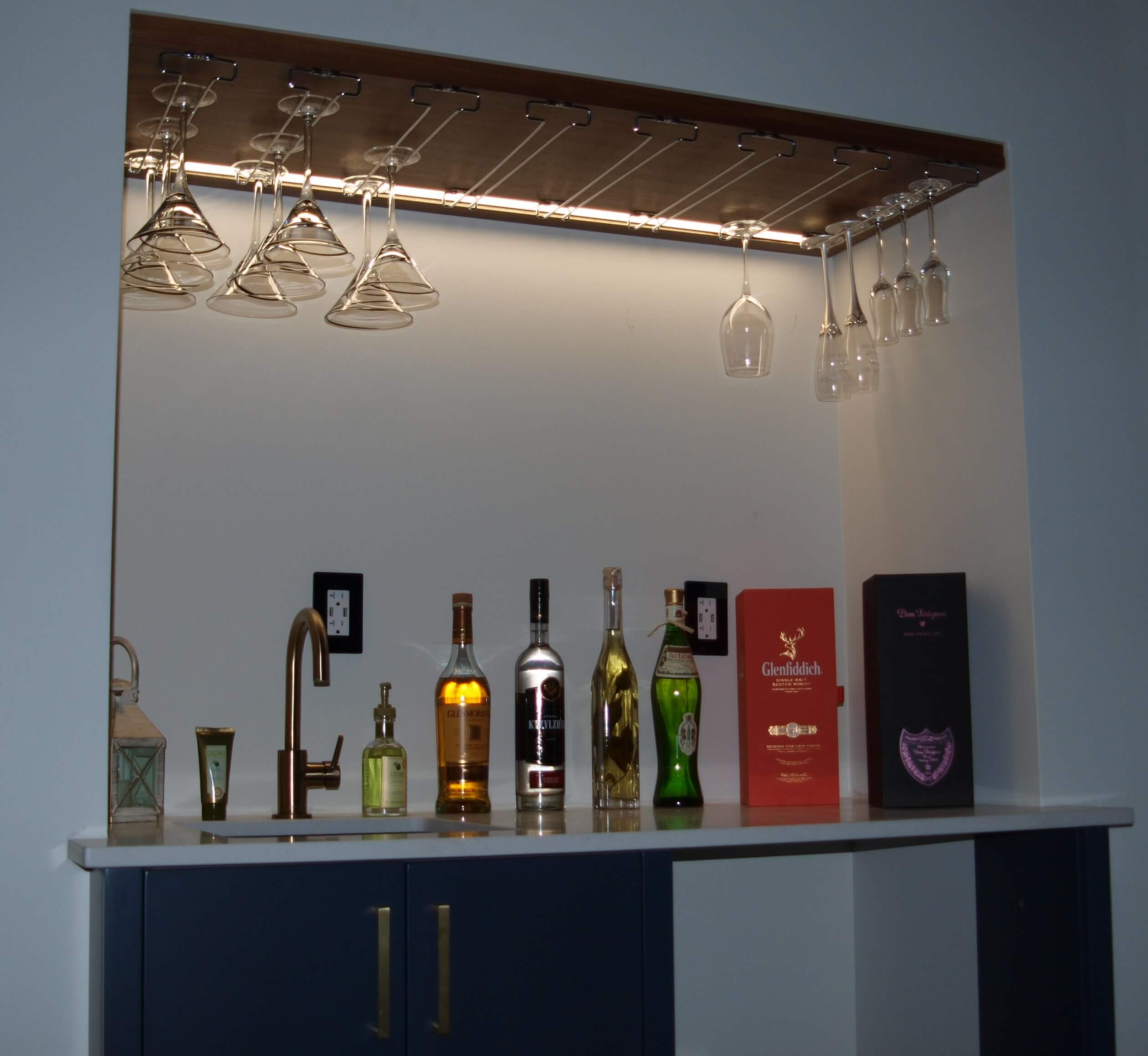 Under-shelf bar lighting with bottles and hanging glasses