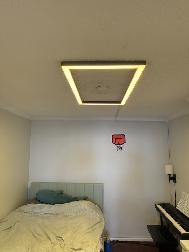 Custom rectangular LED ceiling fixture in warm white illuminating a windowless bedroom