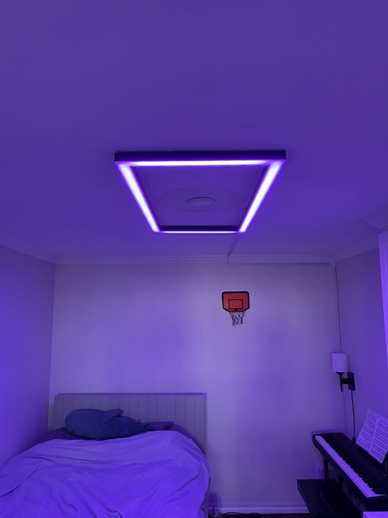 Custom rectangular LED ceiling fixture glowing purple in a windowless bedroom